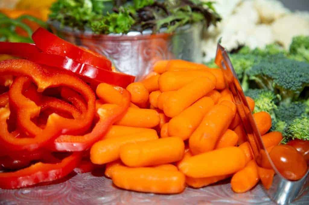 Fresh sliced red bell peppers, baby carrots, and broccoli representing vibrant, healthy produce from the Gulf Coast. Ideal for seafood and farm-fresh regional cuisine.