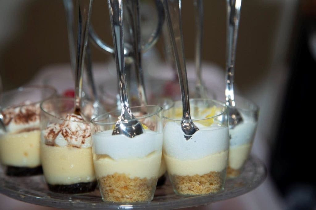 1. Elegant serving of individual cheesecake parfaits with graham cracker crust, creamy filling, and whipped topping, perfect for Gulf Coast event catering.
